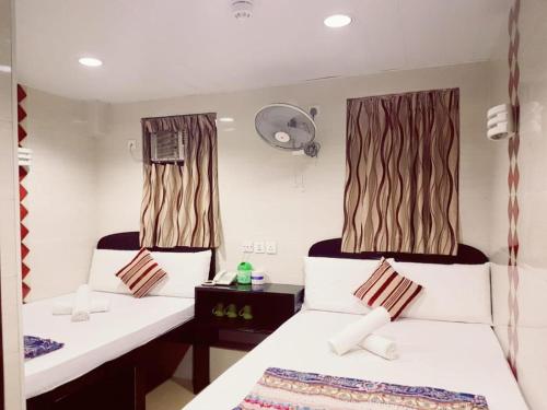 a bedroom with two beds and a fan at Payless Guest House A2 in Hong Kong