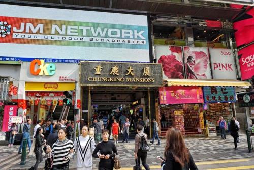 un grupo de personas caminando por una concurrida calle de la ciudad en Payless Guest House A2, en Hong Kong