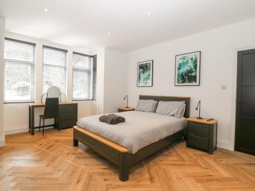 a bedroom with a bed and two tables and two windows at Park View in Llandudno