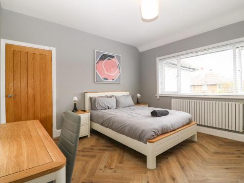 a bedroom with a bed and a table and a window at Park View Upper in Llandudno