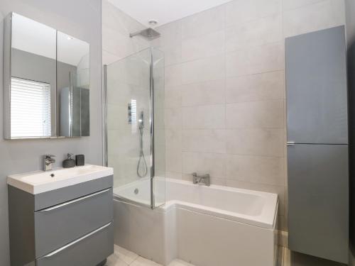 a bathroom with a tub and a sink and a shower at Park View Upper in Llandudno