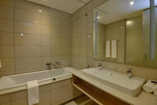 y baño con lavabo, bañera y espejo. en Luxury Apartment Sandton , NO Loadshedding en Johannesburgo