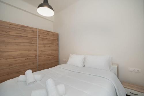 - une chambre avec un grand lit blanc et une tête de lit en bois dans l'établissement 'Santa Marina Detached Cozy House In Egaleo, à Athènes