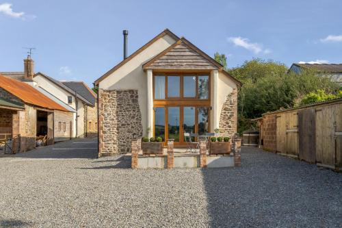 a small house with a window on a gravel driveway at Tumbledown Barn in Knowstone