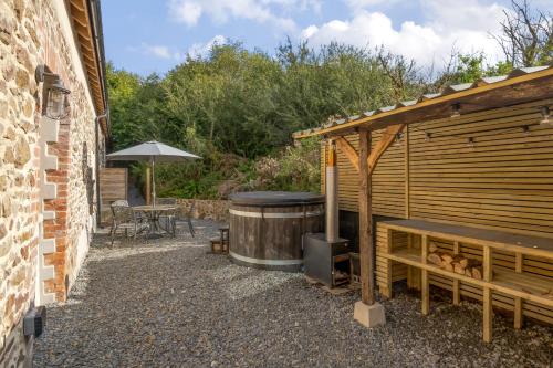 a wooden building with a hot tub next to a patio at Tumbledown Barn in Knowstone