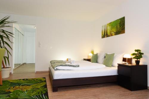 Schlafzimmer mit einem Bett mit weißer Bettwäsche und grünen Kissen in der Unterkunft RELAX - GREEN mit Pool und Sauna in Scheidegg