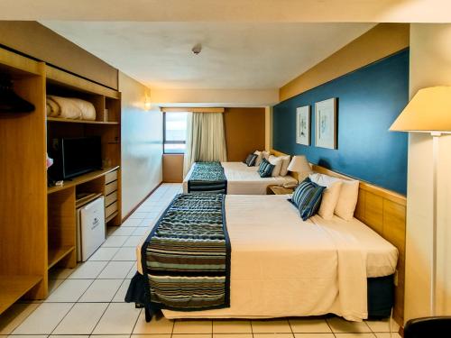 a hotel room with two beds and a tv at Reymar Hotel Maceió in Maceió