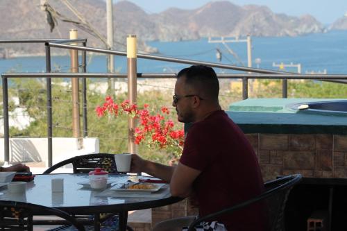 a man sitting at a table with a plate of food at Sunset Taganga Hotel in Taganga