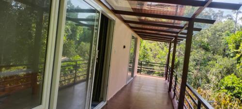 un balcón de una casa con vistas al bosque en Katakeri Deluxe Holiday Homes, en Madikeri