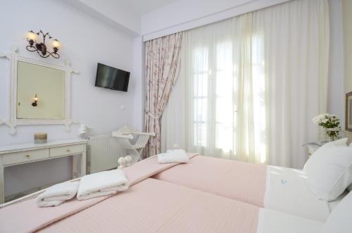 a white bedroom with a large bed and a mirror at Kymata Hotel in Naxos Chora