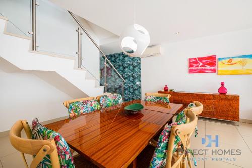 a dining room with a wooden table and chairs at Villas Rocha in Albufeira
