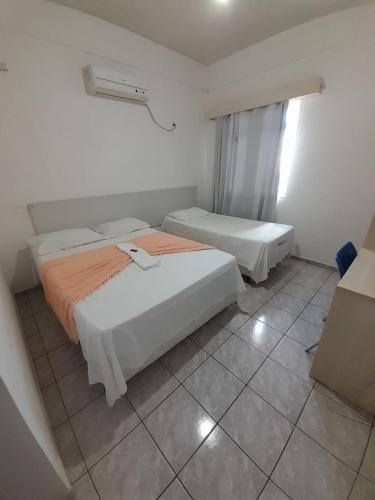 a bedroom with two beds and a window at Hotel e Pousada Mape Ltda in Guanambi
