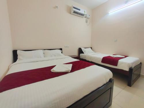 - 2 lits dans une chambre avec des draps blancs et rouges dans l'établissement LE TOWNSHIP RESIDENCY, à Pondichéry
