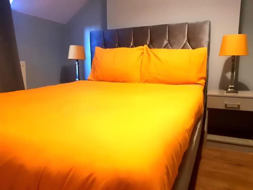 a large bed with yellow sheets and pillows at Central Reading 2 Wash Rooms FREE PARKING in Reading