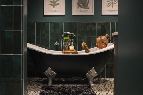 a woman sitting in a bath tub in a bathroom at The Blended Barn in Stratford-upon-Avon