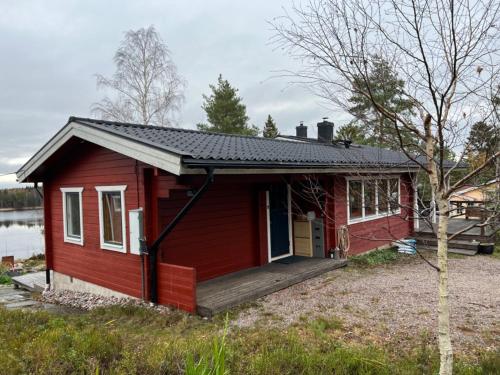ein rotes winziges Haus mit einer Veranda und einer Terrasse in der Unterkunft Värmdö in Värmdö
