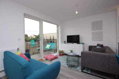 a living room with a blue chair and a couch at 5* Cambridge Boutique Apartment in Trumpington