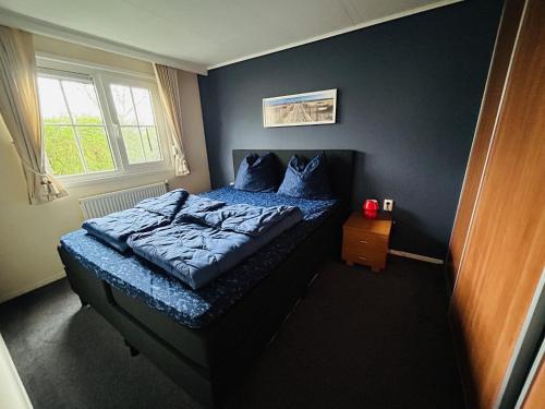 - une chambre avec un lit doté de draps bleus et une fenêtre dans l'établissement NV 206 - Beach Resort Nieuwvliet Bad, à Nieuwvliet