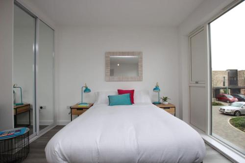 a large white bed in a room with large windows at 5* Cambridge Boutique Apartment in Trumpington