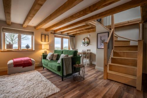 a living room with a green couch and stairs at Piglet's Hideaway in Stratford-upon-Avon