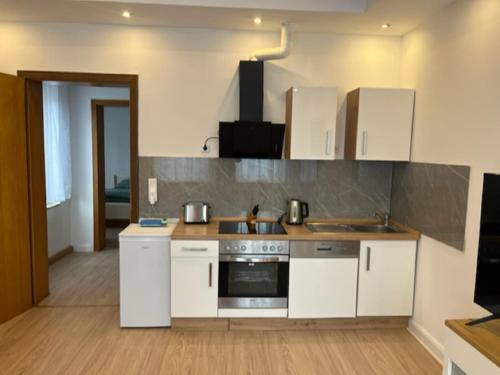 cocina con armarios blancos y fogones en City Apartment, en Bad Sassendorf