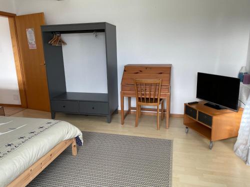 a bedroom with a bed and a desk and a television at Les Rossets in Boudry
