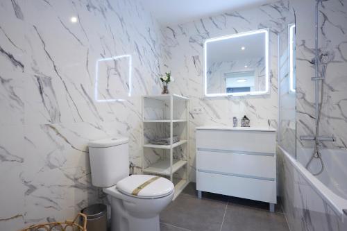 a white bathroom with a toilet and a mirror at Three bedroom Two bathroom apartment Close to Beach in Barcelona