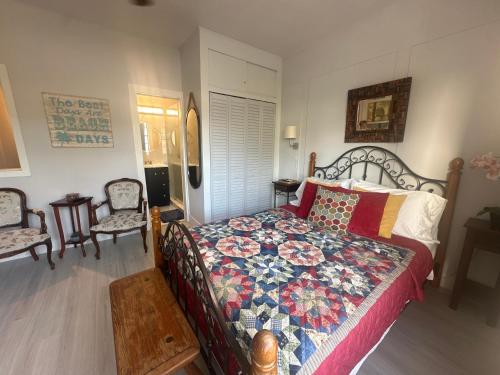 a bedroom with a bed with a quilt and two chairs at Dream Studio on the Beach in Miami Beach