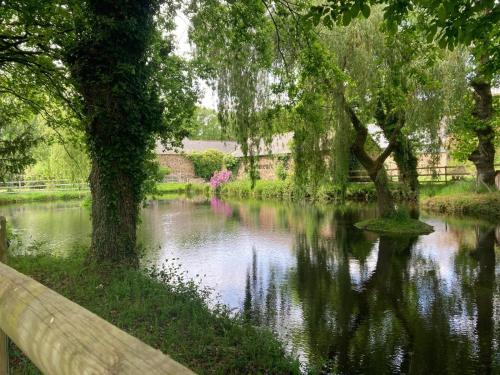 a river with trees and a fence next to it at La demeure romantique in Bazouges-sous-Hédé
