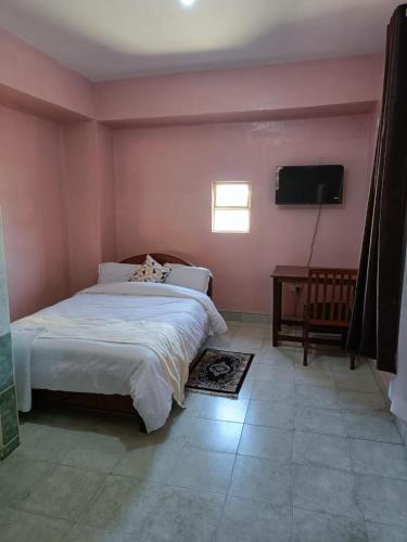 a bedroom with a large bed and a flat screen tv at Sislink Suites in Nairobi