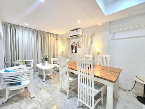 a dining room with a wooden table and white chairs at 39 Living Pattaya in Pattaya
