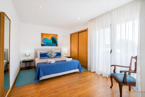 a bedroom with a blue and white bed and a chair at Villas Rocha in Albufeira