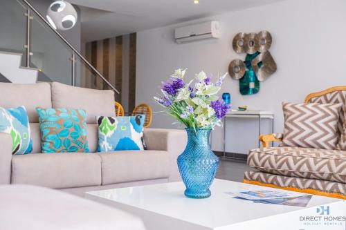 a blue vase with flowers on a table in a living room at Villas Rocha in Albufeira