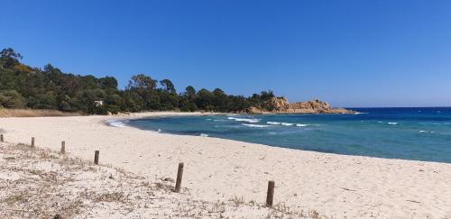 een strand met een hek en de oceaan bij Auberge de Cannedda in Sari Solenzara