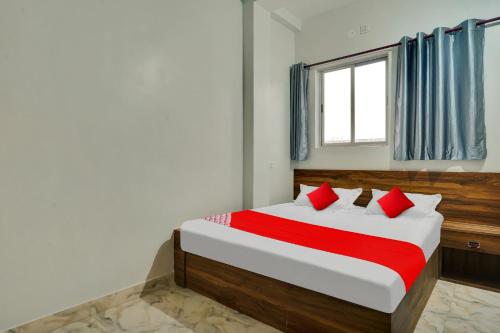 Schlafzimmer mit einem Bett mit roten Kissen und einem Fenster in der Unterkunft OYO Flagship Hotel The Cloud in Jāmul