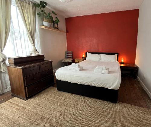 a bedroom with a large bed and a red wall at Cottage Hideaway with Garden in Bristol