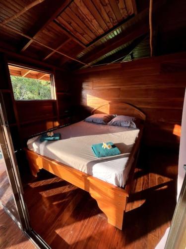 a small bed in a wooden room with a window at Casa’ Mapola : typical beach jungle house in Pavones