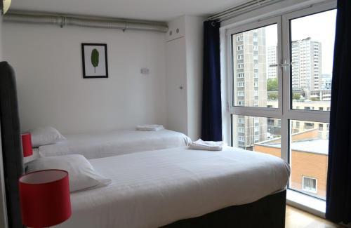 two beds in a room with a large window at Access Apartments City in London