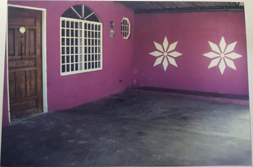 a room with a pink wall with flowers on the wall at Betohouse in San Miguelito