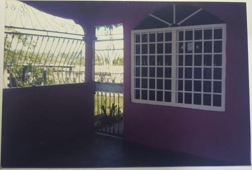 fioletowe drzwi z oknem i płotem w obiekcie Betohouse w mieście San Miguelito