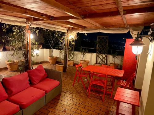 a patio with a red couch and a table and chairs at Il Tramonto su Tivoli in Tivoli