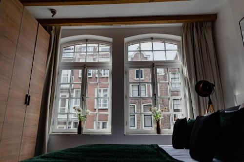 een slaapkamer met twee ramen met bloemen erin bij Kerkstraat Residence in Amsterdam