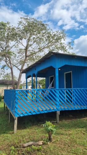 a blue building in a field with a tree at Vista do Ubim in Paricatuba