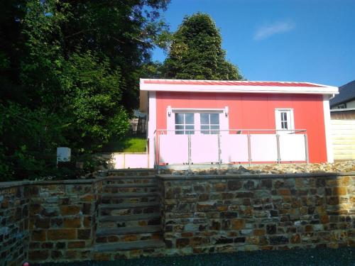 uma pequena casa rosa no topo de uma parede de tijolos em Ferienhaus in Bad Marienberg Westerwald mit Grill und Terrasse em Bad Marienberg