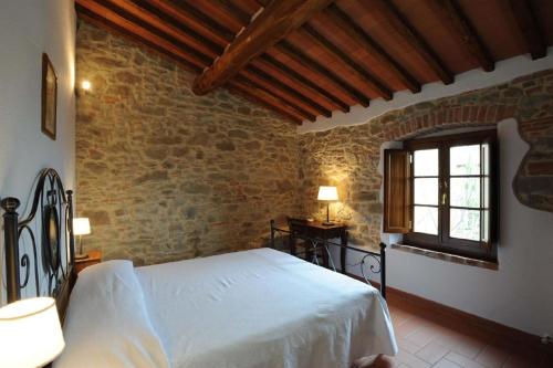 a bedroom with a white bed in a stone wall at Große Ferienwohnung in Rapale mit Terrasse, gemeinsamem Pool und Grill und Panoramablick in Rapale