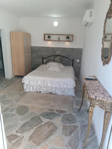 a bedroom with a bed and a table and a mirror at Ξενώνας in Nea Kalikratia
