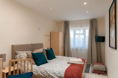 een kleine slaapkamer met een bed met blauwe kussens bij Beautiful and spacious home in Londen