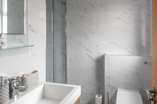 een witte badkamer met een wastafel en een spiegel bij Beautiful and spacious home in Londen