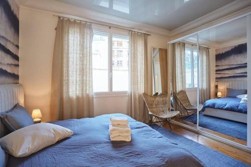 um quarto com uma cama azul e um espelho em Apartment Arc de Triomphe/ Champs Elysée by Studioprestige em Paris