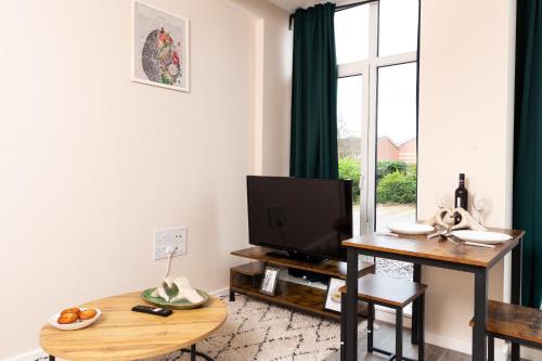 a living room with a television and a table with a tableablish at Stylish Living: 1BR Apt near MCR Central in Manchester